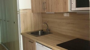 Een keuken met houten kastjes, een roestvrijstalen spoelbak, een magnetron en een vaatwasser.