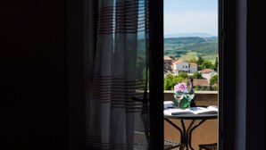 A balcony with a table set for two, featuring a book, a vase with flowers, and a bottle. - San Gimignano Town Garden - 10 pax (San Gimignano)