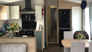 Una cocina moderna con estufa, lavabo y armarios, un comedor con mesa y sillas, y una sala de estar con sofá.
