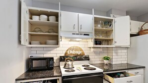 Una cocina con gabinetes blancos, una estufa, un microondas y un cartel que dice 'Chicago'.
