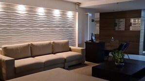 A modern living room with a sofa, a coffee table, and a decorative wall panel. - Ritz Suítes Maceió Flat particular (Maceió)