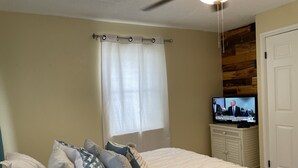 A bedroom with a bed, pillows, a television, and a window with curtains. - The Island Life Condo@ Long Reef with Separate Bedroom + True Ocean View (Christiansted)