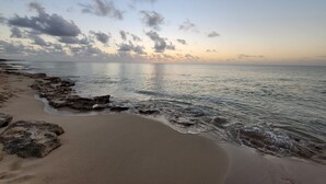 A beach with calm waters, scattered rocks, and a clear sky. - The Island Life Condo@ Long Reef with Separate Bedroom + True Ocean View (Christiansted)