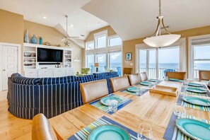 Relax in this stylish living area with a sofa, dining table, and TV, surrounded by ocean views.
