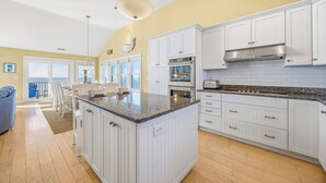 A spacious kitchen with white cabinetry, a granite countertop, and a large island. There are two ovens, a microwave, and a toaster. - Soundfront w/ Pool, Hot Tub, Elevator, Game and Media Rooms, Windsports Access (Avon)