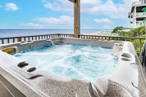 Relax in a hot tub on a balcony with ocean views.