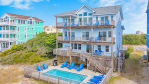 A multi-story beachfront property with a pool and outdoor seating. - Soundfront w/ Pool, Hot Tub, Elevator, Game and Media Rooms, Windsports Access (Avon)