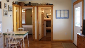 Ein gemütliches Zimmer mit Holztisch und -stühlen, einem Bett und einer Kommode.