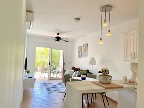 Un amplio espacio de sala con ventilador de techo, una mesa de comedor y una zona de cocina con armarios y encimera.