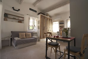 Ein gemütliches Wohnzimmer mit einer Couch, einem Esstisch mit Stühlen, einem Bücherregal und einer großen Holztür.