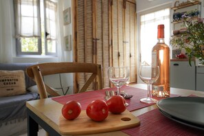 A wooden table with a cutting board, two tomatoes, a wine bottle, and a glass. - Cottage-Ensuite with Bath-Garden view-Cottage Mirabeau (Aix-en-Provence)