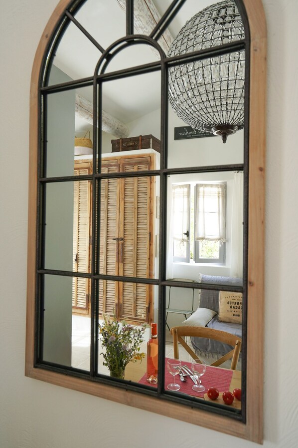 Una habitación con un espejo arqueado grande, un armario de madera y una mesa de comedor con sillas.