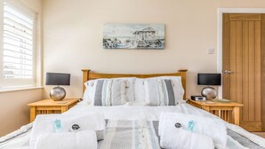 Una camera da letto con un letto di legno, due comodini con lampade, un quadro appeso al muro e una porta in legno.