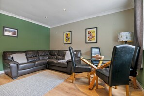 A living room with a sectional sofa, a glass coffee table, and two chairs.