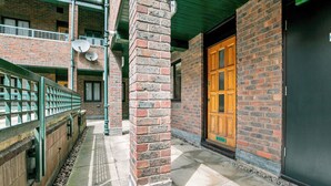 A brick building with a wooden door, a brick pillar, and a green roof. - 5 St Georges House · Lovely 1-Bed Apartment Right in the Heart of York - Pass the Keys (York)