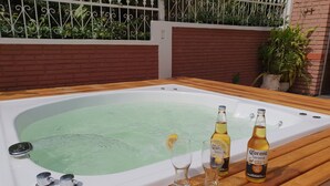 Un bain à remous avec deux bouteilles de bière Corona et deux verres posés sur une table en bois.