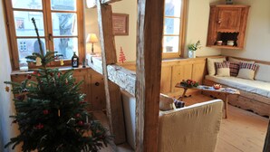 Una habitación acogedora con un banco de madera, un pequeño árbol de Navidad y un mueble de madera.