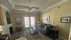 A living room with a ceiling fan, a sofa, a coffee table, and a fireplace. - Breezy Beach Retreat (Gulfport)
