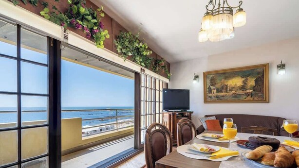 Zona pranzo con vista mare, un quadro appeso al muro e un televisore su un tavolo.