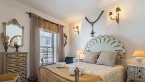 Una camera d'albergo con un letto grande, una cassettiera, uno specchio e una finestra con tende.