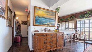 Una camera spaziosa con pavimento in legno, un quadro di grandi dimensioni appeso alla parete, un'area pranzo con sedie e tavolo, e un armadio con cassetti.