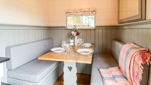 Un rincón comedor acogedor con una mesa de madera dispuesta para dos personas, flanqueada por bancos acolchados.