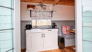 Una cocina compacta con un armario blanco, una cafetera y un hervidor en la encimera.