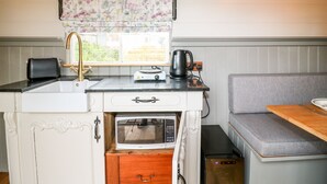 Una kitchenette compacta equipada con microondas, tostadora, hervidor y un lavamanos pequeño.