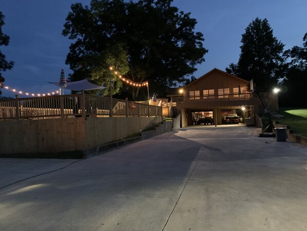 A two-story building with a covered outdoor area, a wooden fence, and string lights.