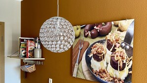 Un comedor con una mesa de madera, un cuenco de fruta, un jarrón decorativo y un cuadro colgado en la pared con imágenes de comida.