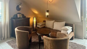 Un dormitorio tipo loft acogedor con techo curvo, un sofá mullido, una mesa de centro redonda y una lámpara decorativa.