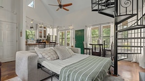 Un dormitorio con cama, una escalera y vista al exterior.