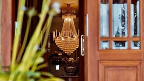 A wooden door with glass panels, a chandelier, and a potted plant in the foreground. - Villa Brunnby (Nyhamnslage)