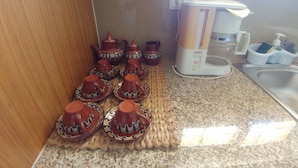 A kitchen with a coffee maker, a sink, and a woven mat with teapots.