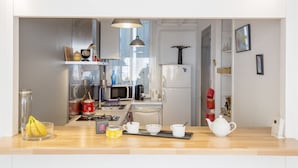 A modern kitchen with a wooden countertop, a microwave, a coffee maker, and a refrigerator.