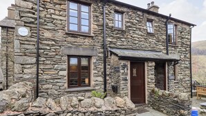 A stone building with a dark brown door and windows, a stone wall in front, and a sign that reads "The Clyne House." - The Curious Orange (Windermere)