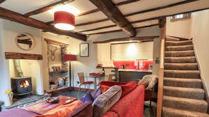 A cozy living room with a fireplace, a sofa, and a staircase leading to a kitchen. - The Curious Orange (Windermere)