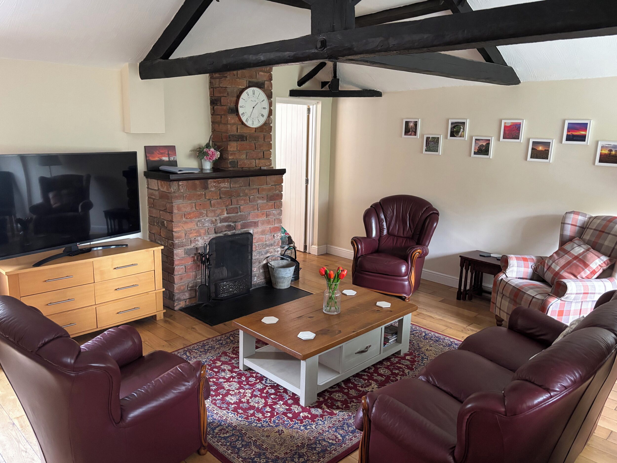A living room with a brick fireplace, leather sofas, a wooden coffee table, and a television.