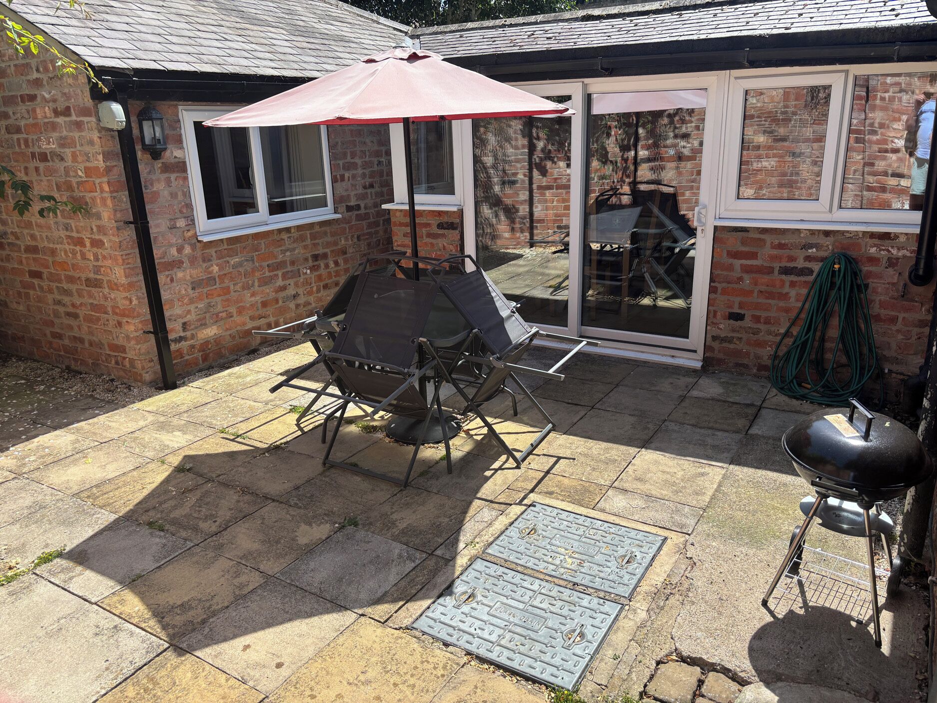 Eine Terrasse mit Grill, Tisch und Stühlen sowie einem überdachten Bereich.