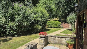 A patio area with stone seating, a small table, and a decorative bird statue. - Claire Cottage (Selby)