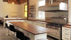 Eine moderne Küche mit einer Holztischinsel, Edelstahlgeräten und einem großen Fenster für natürliches Licht.