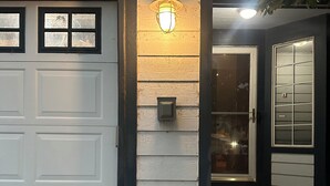 Une porte de garage avec un luminaire au-dessus, une boîte aux lettres et une porte avec une fenêtre.