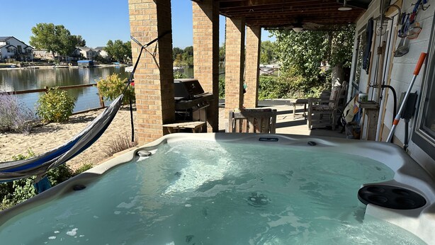 Un espace avec un bain à remous offrant une vue sur un lac, un hamac et du mobilier d’extérieur.