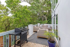 Un patio exterior con una parrilla, mobiliario de mimbre y una planta en maceta.