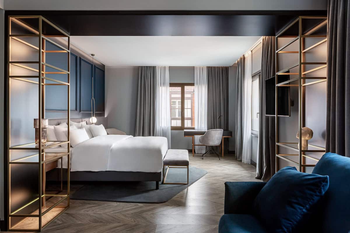 A modern hotel room with a large bed, a desk, and a TV.