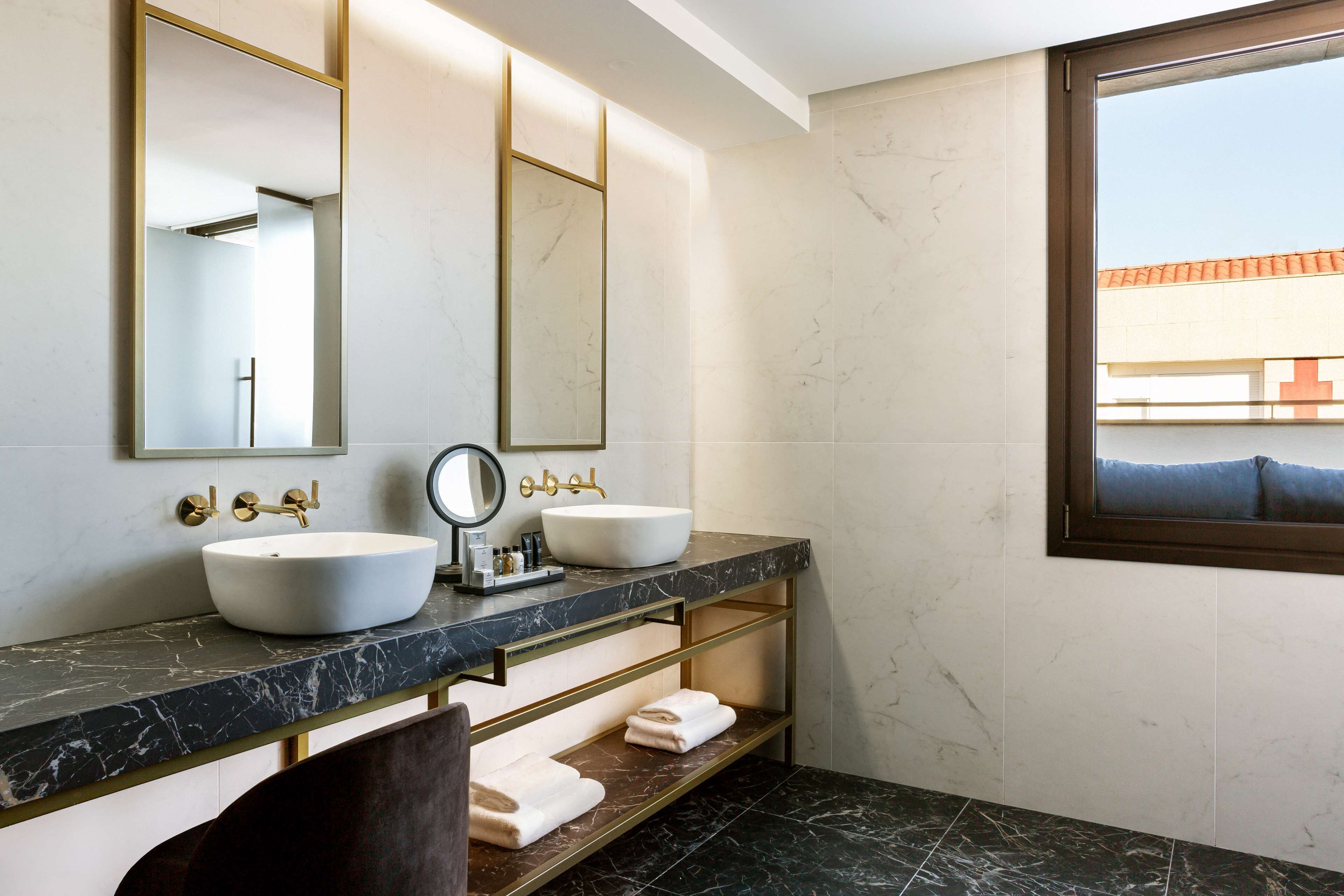 Un baño moderno con dos lavamanos, un espejo grande y una ventana con vistas al exterior.