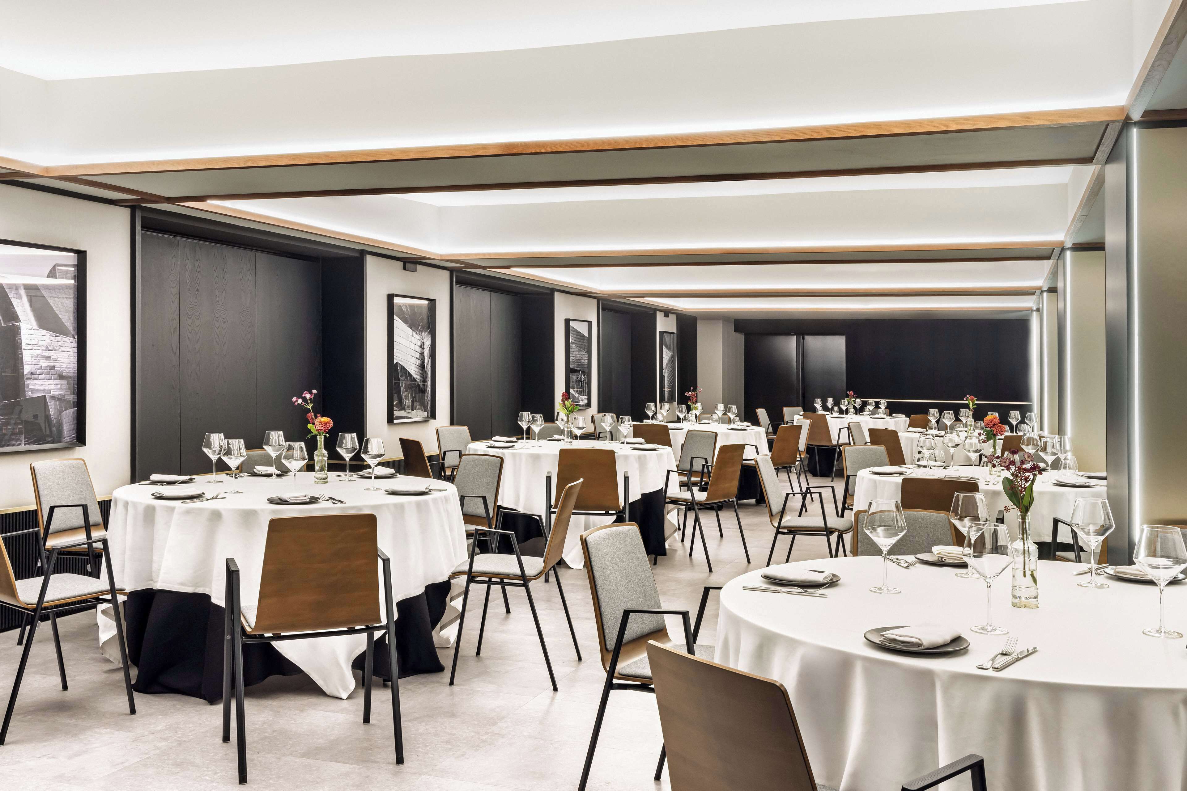 Un comedor amplio con mesas redondas, sillas y vajilla dispuesta con cuidado.