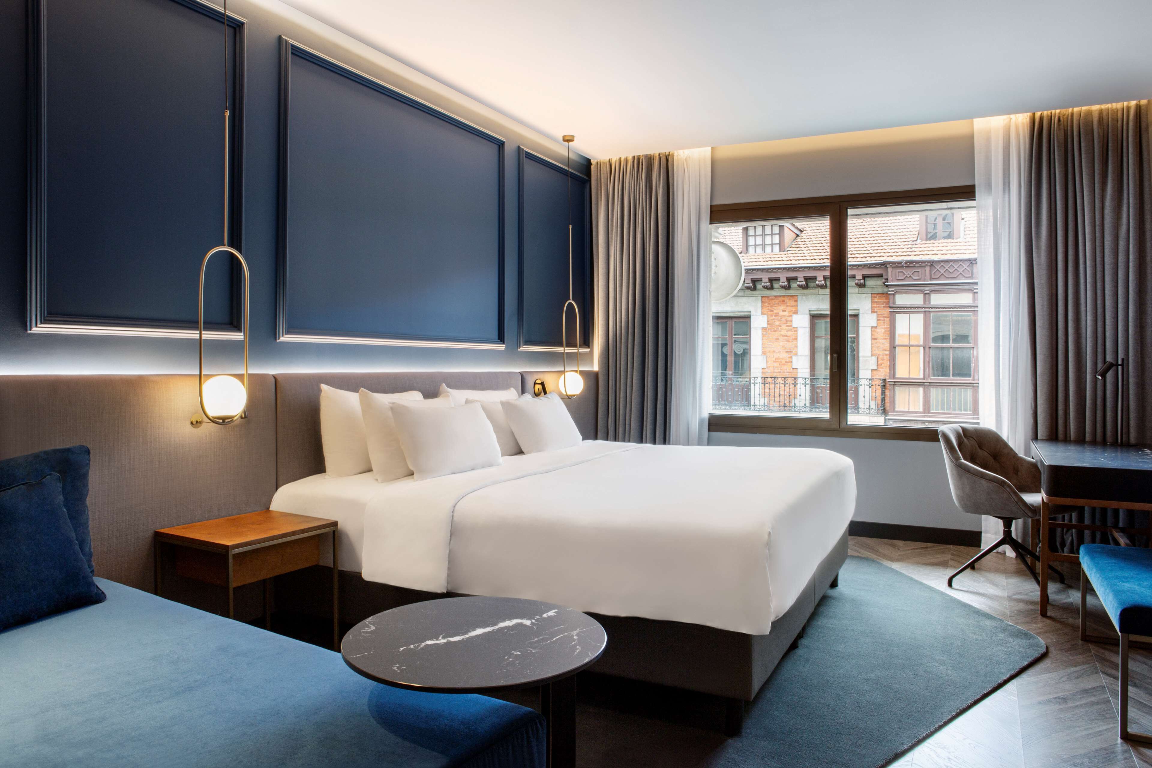 Een moderne hotelkamer met een groot bed, een bureau en uitzicht op de stad.