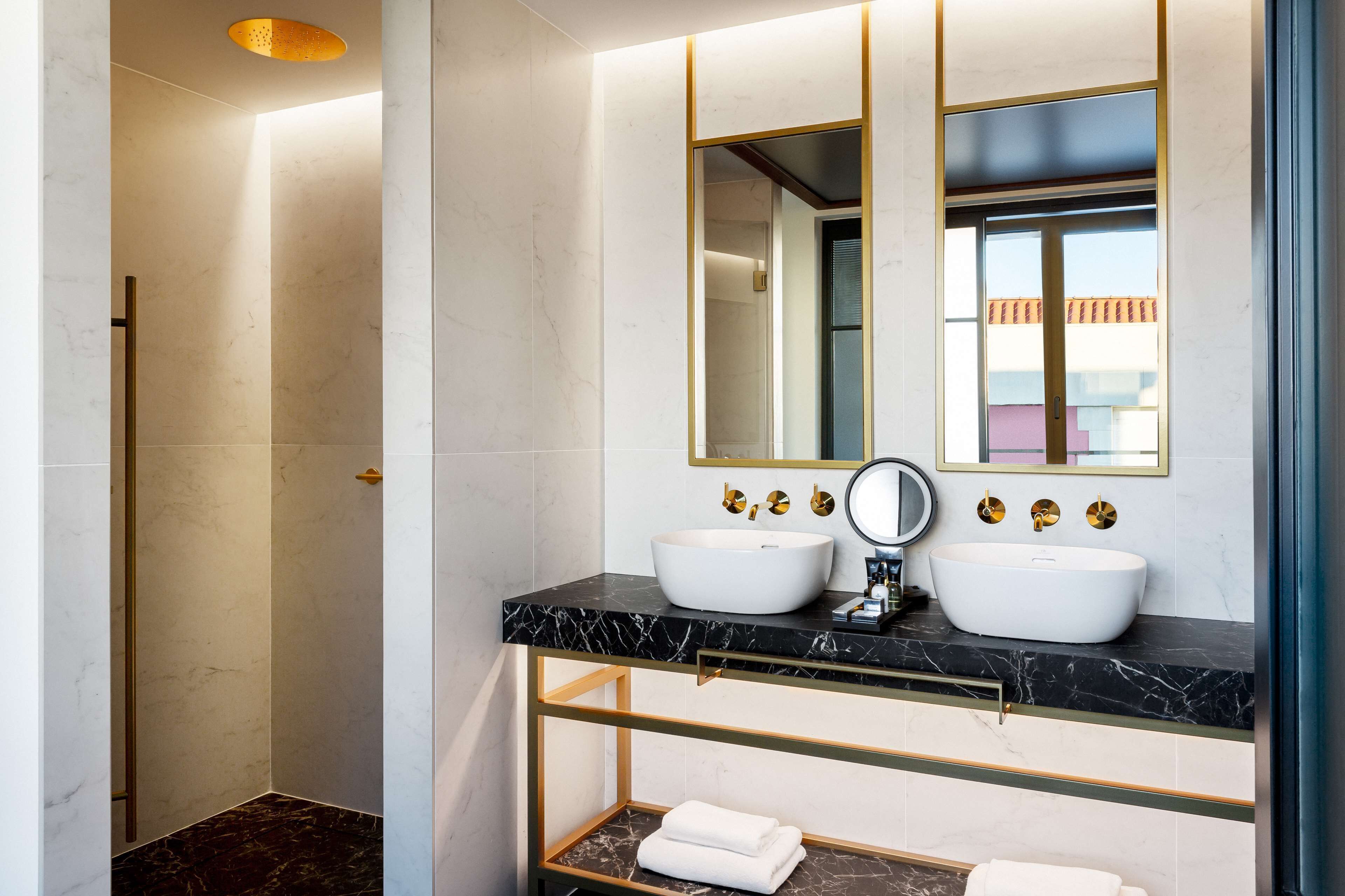 Un baño moderno con dos lavamanos blancos, un espejo grande y una zona de ducha.
