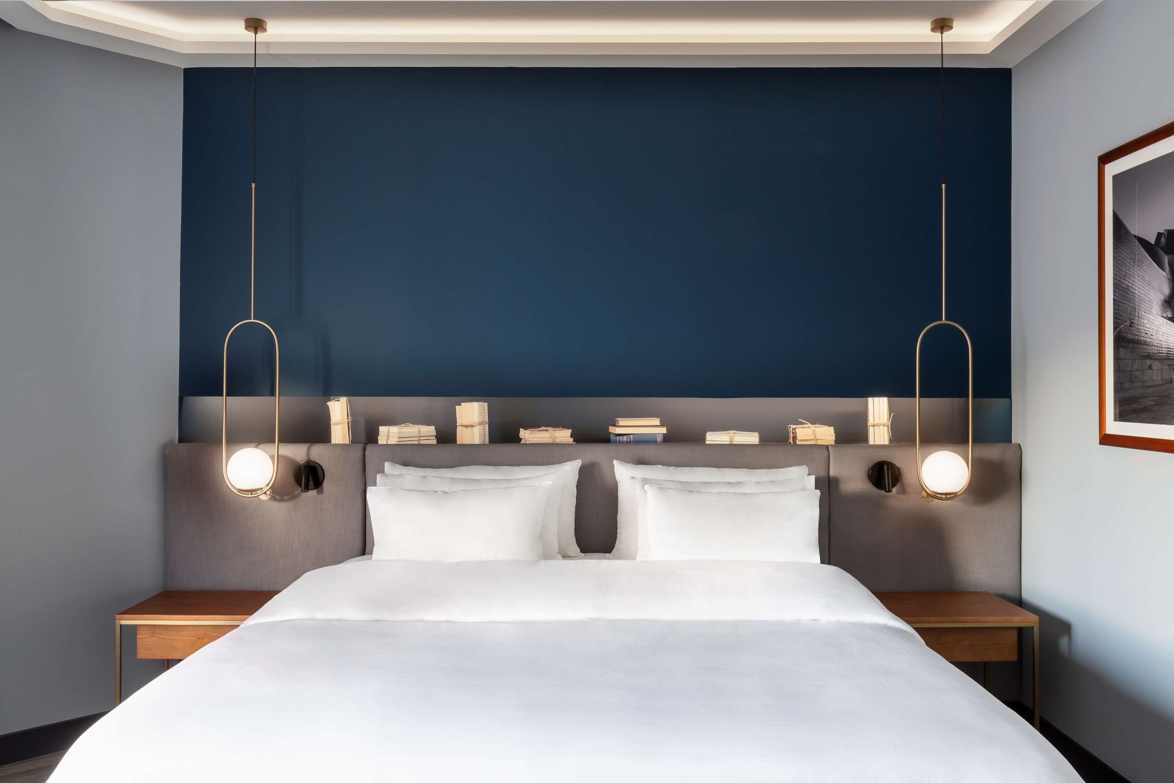 Une chambre d’hôtel moderne dotée d’un grand lit, de tables de chevet et d’une tête de lit avec éclairage intégré.